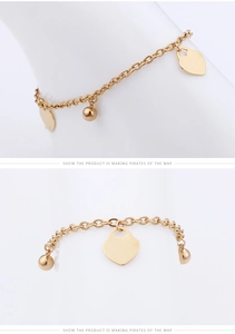 Detailed close-up of gold heart anklet with polished heart and ball charms on a chain