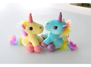Close-up of cute yellow and blue plush unicorn keychains with colorful rainbow manes