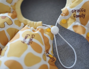 Close-up of giraffe print pet cone with yellow snap buttons and elastic drawstring