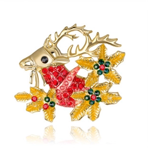 Detailed view of gold reindeer head brooch with green leaves and red crystal rhinestones