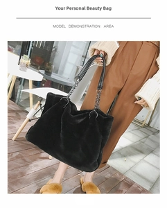 Detail view of black faux fur tote bag with metal chain and leather handles shown on model