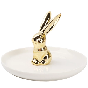 Detail of a white ceramic jewelry tray featuring a polished gold rabbit statuette
