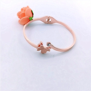Close-up of 18K rose gold butterfly bangle with a sparkling diamond on white background