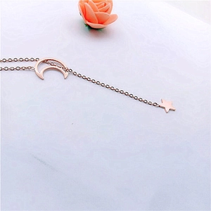 Detail of rose gold star and moon pendant necklace on a minimalist white surface