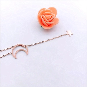 Detail of rose gold crescent moon and star pendant necklace on white background