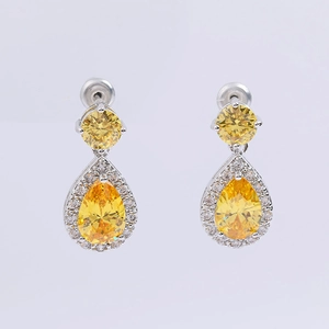 Detailed macro view of yellow teardrop zircon earrings with silver plating and pavé setting