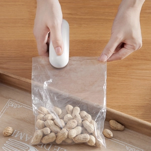 Portable mini handheld food sealer for plastic bags on a wooden desk setting