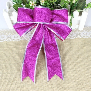 Detail of 25cm purple glitter Christmas bow with silver trim on rustic burlap surface