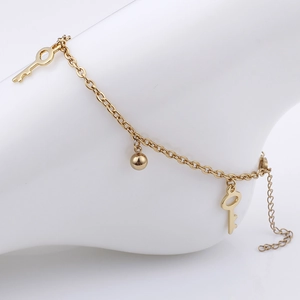 Elegant gold anklet with key and ball charms shown on ankle for summer beach style