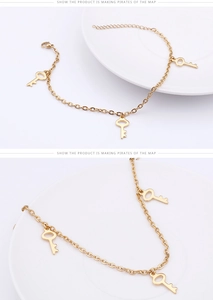 Détail de la chevillère en titane doré avec pendentifs clés sur un plateau blanc