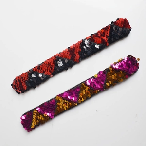 Detail of sequin slap bracelets showing red and purple scale textures with velvet lining