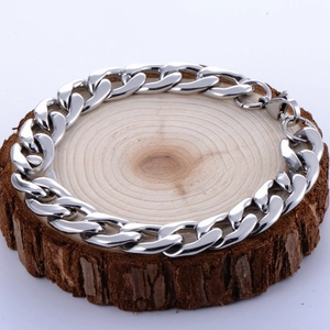 Macro shot of silver stainless steel Cuban chain bracelet on wood with lobster clasp