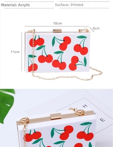 Detail view of white acrylic square evening clutch with cherry print and gold hardware