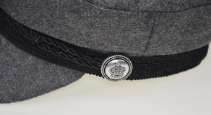 Macro shot of silver metal crown buckle and black woven band on grey wool hat