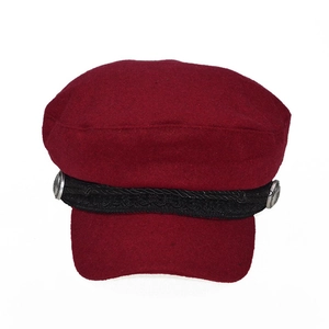 Detail of burgundy wool newsboy cap featuring black braided strap and silver metal buttons