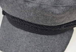 Detail of grey wool felt newsboy cap with black braided rope and precise stitching