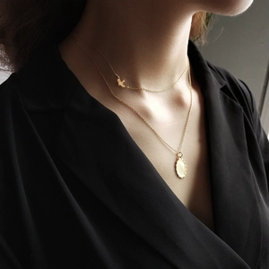 Detail of a layered 925 sterling silver gold necklace with bird and oval pendants
