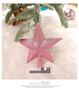 Close-up of pink glitter Christmas tree star topper on a soft white plush rug