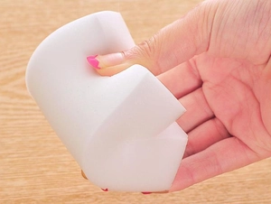 Close-up showing the high flexibility and compression of a white nano cleaning sponge