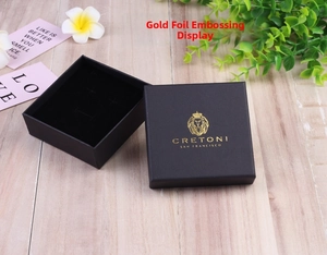 Close-up of black square jewelry box with gold logo and soft velvet lining inserts