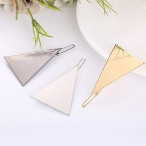 Close-up of geometric triangle metal hair clips in gold, silver, and gunmetal finishes