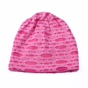 Detailed knit texture of bright pink slouchy beanie with stylish distressed hole design