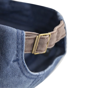 Close-up of blue washed denim baseball cap with brown adjustable strap and metal buckle