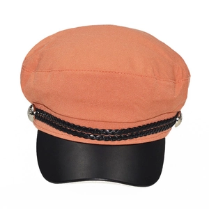Detail of orange newsboy cap featuring black leather brim and woven cord decoration
