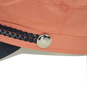 Detail of orange baker boy hat showing black braided cord and golden embossed metal buttons
