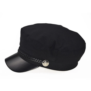 Detail of navy baker boy hat featuring black twill fabric and silver crest button