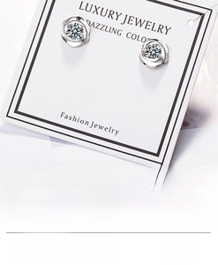 Detailed view of silver flower stud earrings with sparkling cubic zirconia on a jewelry card