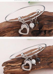 Détail de bracelets cœur en argent avec perles de marbre et œil de tigre sur bois