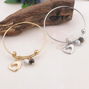 Bracelets cœur en or et argent avec perles de marbre et d'œil de tigre sur socle en bois