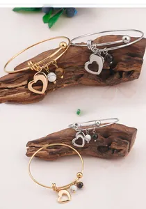Détail de bracelets cœur en or et argent avec perles marbrées sur bois