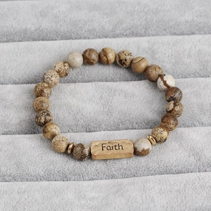 Detailed macro view of natural stone beaded bracelet with antique gold Faith plate