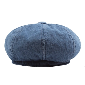 Deep blue washed denim newsboy cap with top button detail on a clean white background