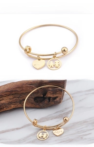 Detail of gold adjustable bangle with Love heart charm and boy girl silhouette pendant