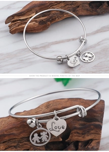 Detail of silver titanium steel couple bracelet with heart love charm and child pendant