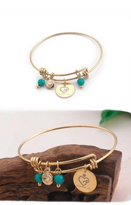 Detail of gold Happy Mother's Day charm bracelet with turquoise beads on wood