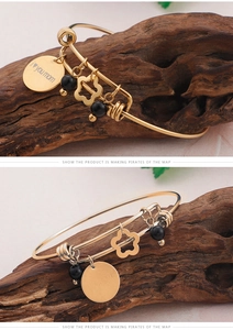 Close-up of golden mom charm bracelet with i love you engraving and black beads on wood