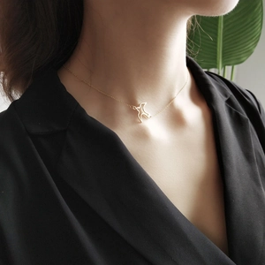 Macro shot of gold bird pendant on minimalist choker chain worn by a female model