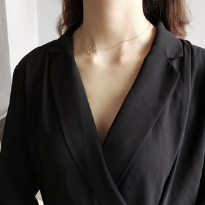 Close-up of a minimalist golden swallow pendant necklace worn on a model's neck
