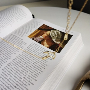 Close-up of a delicate golden bird pendant necklace on an vintage art book page