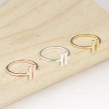Close-up of rose gold, silver and gold dolphin open rings on a wooden surface