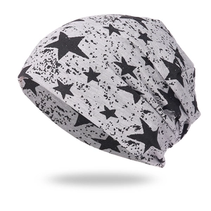 Détail d'un bonnet en maille gris clair avec motif étoile noire et éclaboussures de peinture