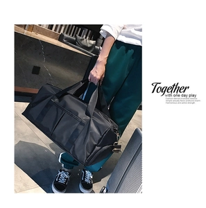 Detail of a black travel bag showing reinforced handles and detachable shoulder strap setup
