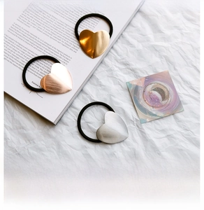 Three metallic heart-shaped hair ties in gold, rose gold and silver on white paper