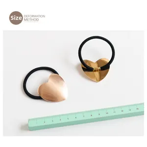 Detailed view of heart-shaped metal hair tie with ruler showing size and glossy finish