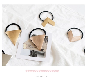 Detail of geometric brushed metal hair ties in gold and rose gold on a soft white cloth