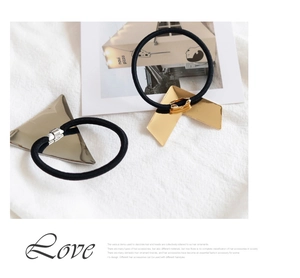 Detail view of black elastic hair ties with gold and silver geometric triangle charms